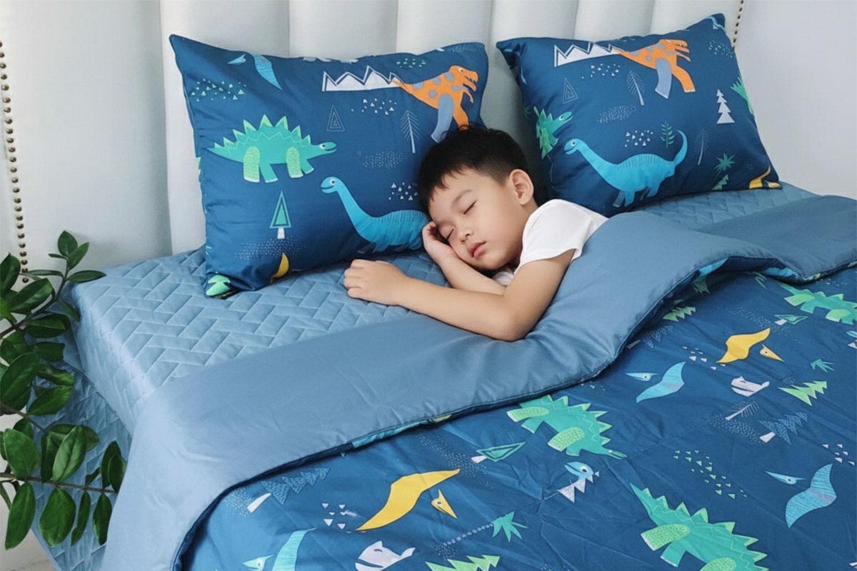 Đứa bé ngủ ngon trên bộ chăn ga cotton Modal khủng long ngộ nghĩnh.